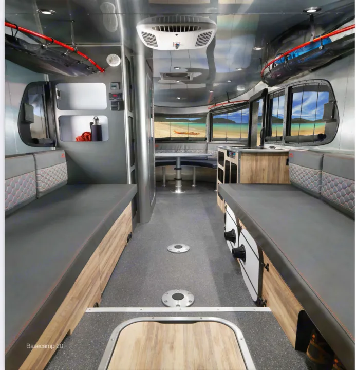 2023 Airstream Basecamp 20X interior — full length view showing both bench seats, U-shaped dinette, panoramic front windows, and wood trim
